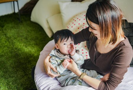 指しゃぶりをする子どもと見守るお母さん