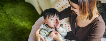 指しゃぶりをする子どもと見守るお母さん